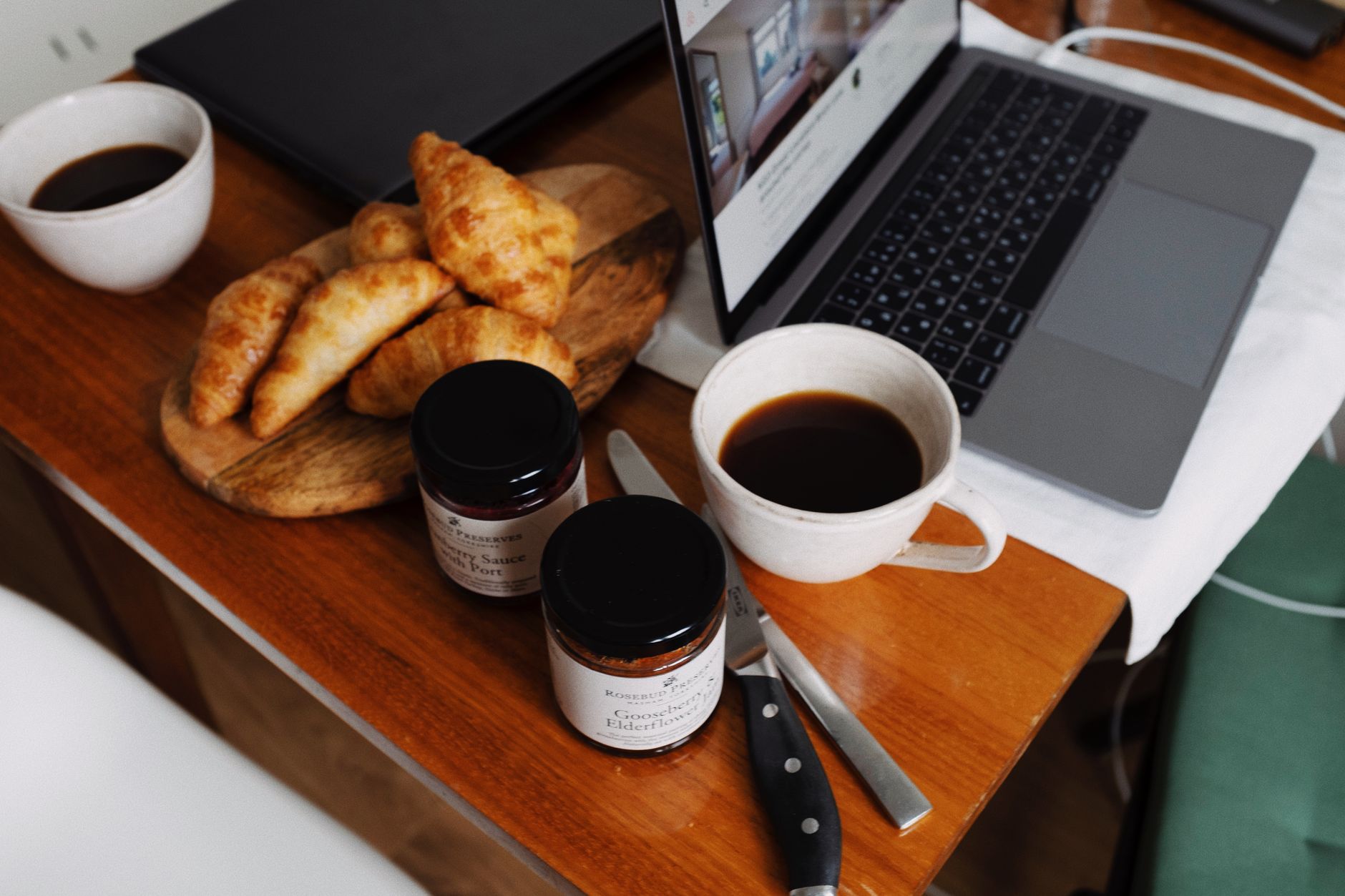Mesa de desayuno con tarros de mermelada, croissants y miel